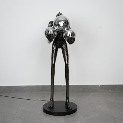 Black abstract sculpture on a gray floor with a white wall background