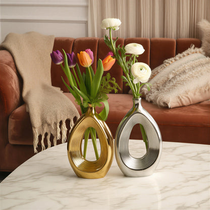 Luxury duo set of ceramic vases featuring contemporary hollow oval silhouettes in gold and silver finishes, ideal for fresh flowers, dried botanicals, console tables and modern designer interiors.