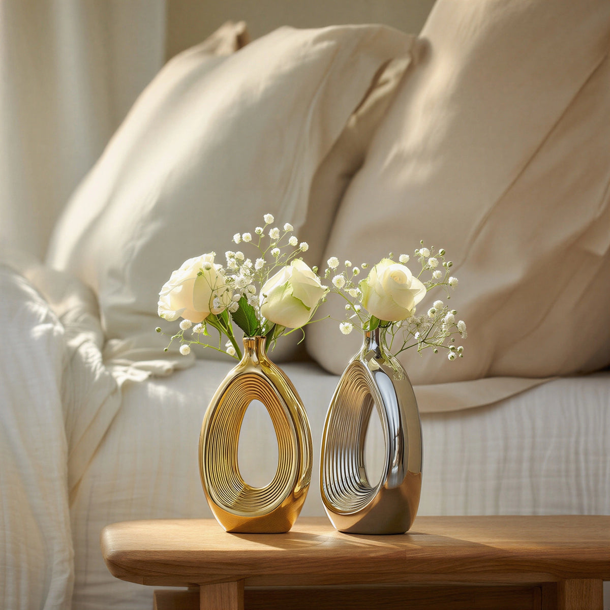 Luxury duo set of ceramic vases featuring contemporary hollow oval silhouettes in gold and silver finishes, ideal for fresh flowers, dried botanicals, console tables and modern designer interiors.