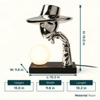 Decorative lamp with a metallic top hat and arm holding a light bulb on a gray background