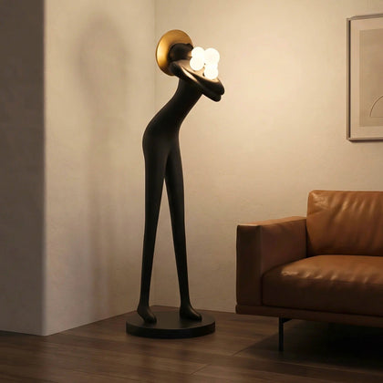 Tall black human-form floor sculpture holding glowing light orbs