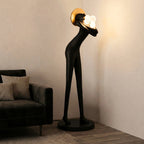 Tall black human-form floor sculpture holding glowing light orbs