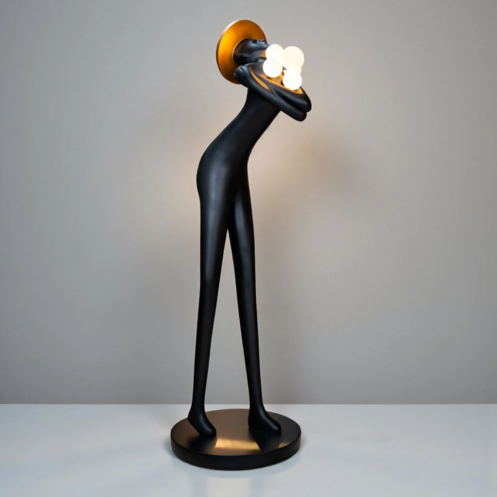 Tall black human-form floor sculpture holding glowing light orbs