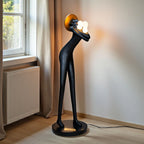Tall black human-form floor sculpture holding glowing light orbs