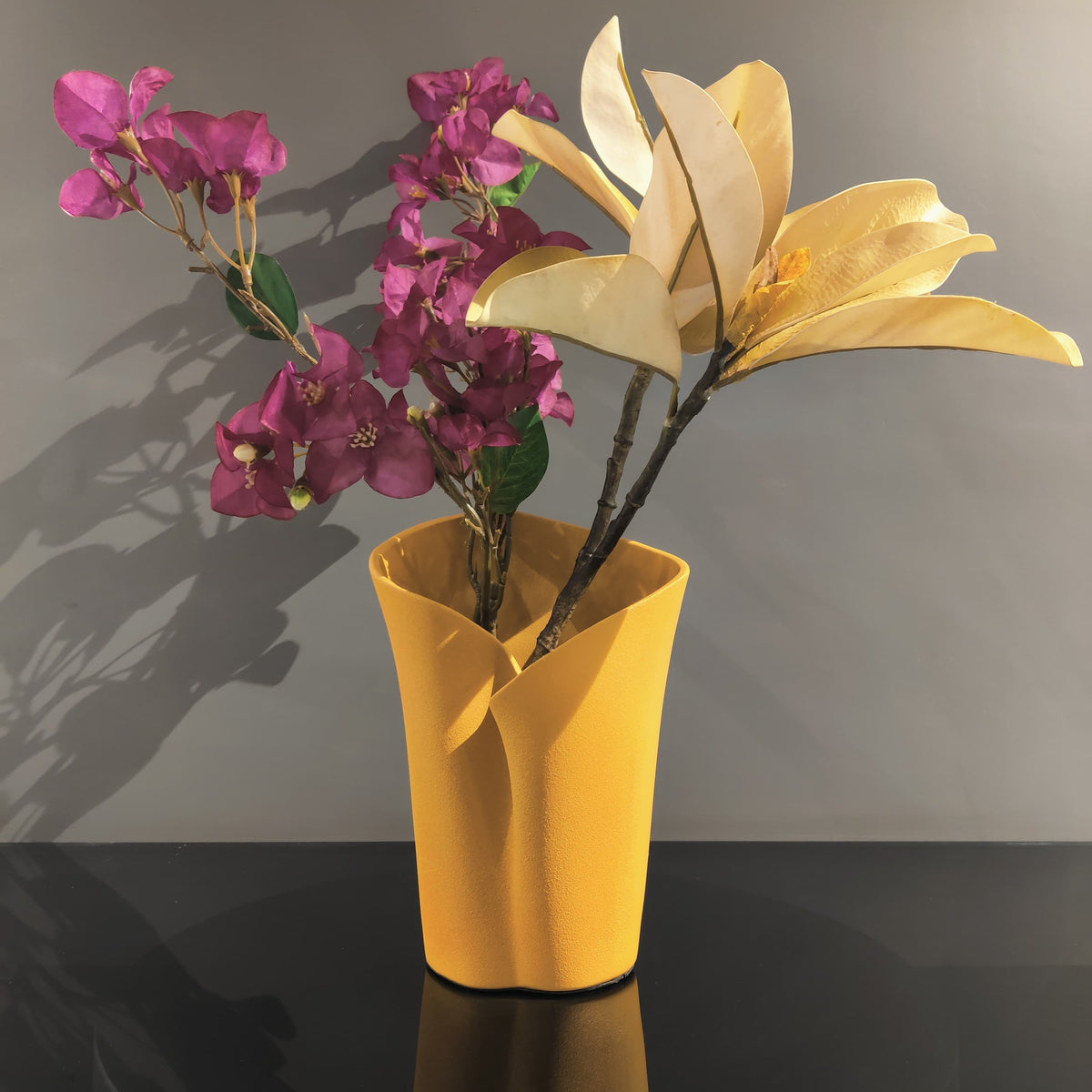 Luxury resin flower vase featuring a contemporary folded sculptural design, available in orange, white and black finishes, perfect for fresh flowers, dried botanicals and modern designer interiors.