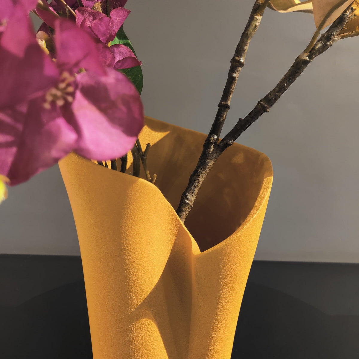 Luxury resin flower vase featuring a contemporary folded sculptural design, available in orange, white and black finishes, perfect for fresh flowers, dried botanicals and modern designer interiors.