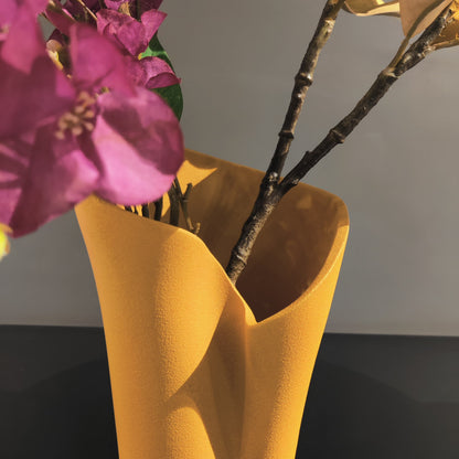 Luxury resin flower vase featuring a contemporary folded sculptural design, available in orange, white and black finishes, perfect for fresh flowers, dried botanicals and modern designer interiors.