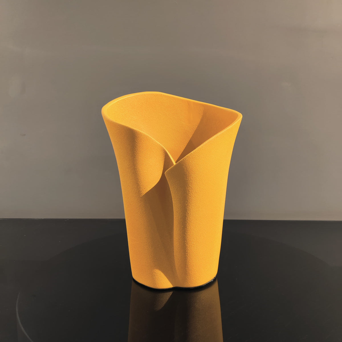 Luxury resin flower vase featuring a contemporary folded sculptural design, available in orange, white and black finishes, perfect for fresh flowers, dried botanicals and modern designer interiors.
