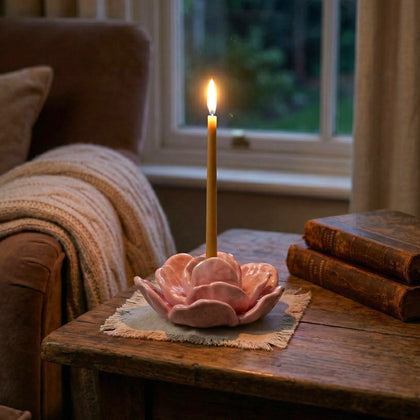 Pink flower holder lit on linen by window