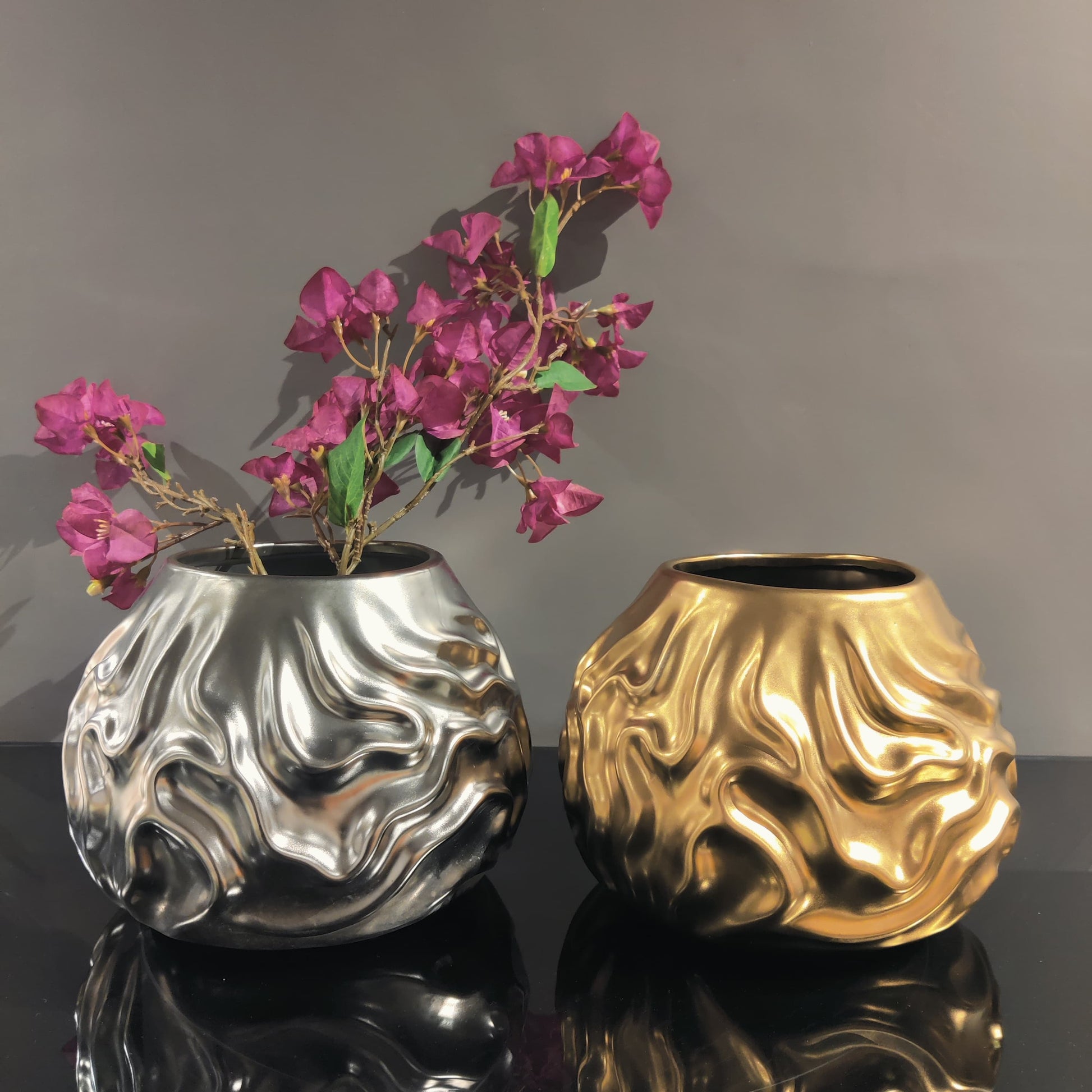 Luxury metallic ceramic decorative vases featuring sculptural fluid textures in gold and silver finishes, ideal for fresh flowers, console tables, dining spaces and modern designer interiors.