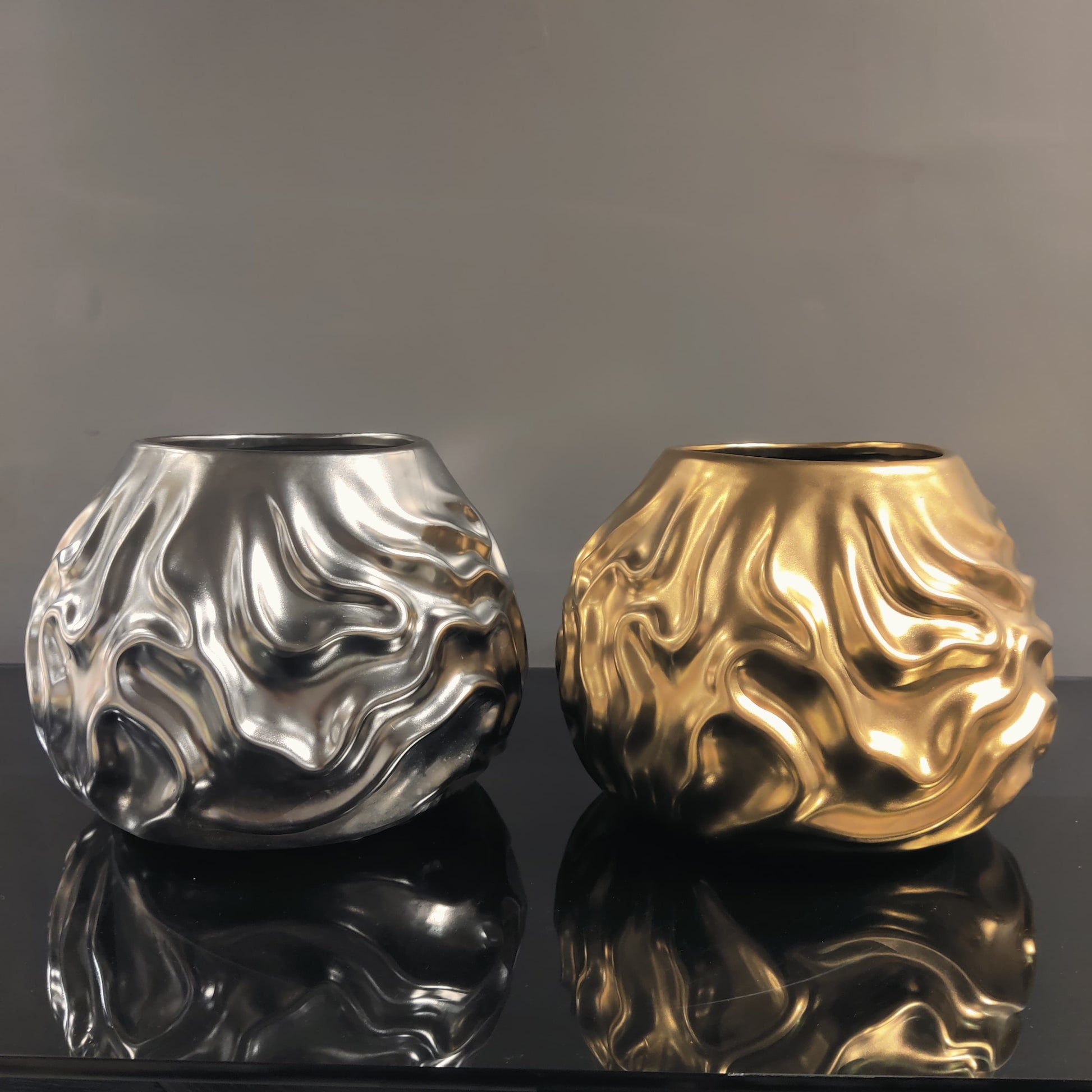 Luxury metallic ceramic decorative vases featuring sculptural fluid textures in gold and silver finishes, ideal for fresh flowers, console tables, dining spaces and modern designer interiors.