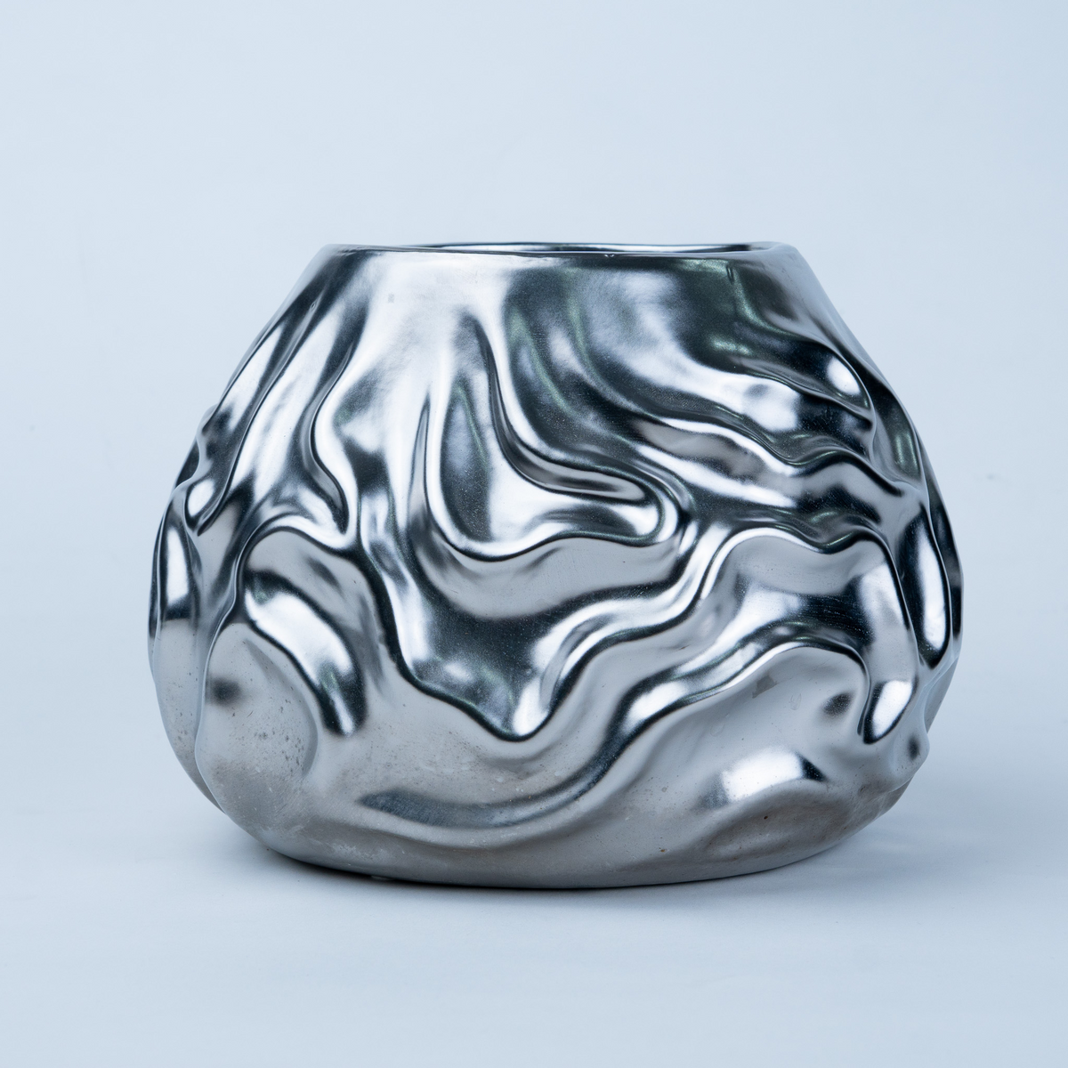 A metallic silver ceramic vase with a wavy, fluid, liquid-metal texture, photographed against a clean light gray background.