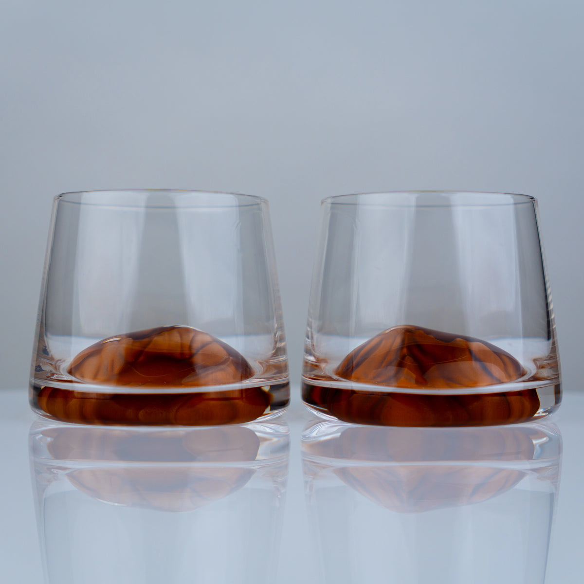Luxury whiskey tumbler glasses with modern transparent finish and amber swirl detailing for elegant entertaining experiences