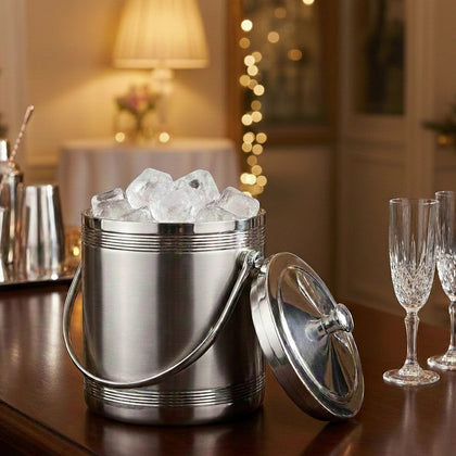 Silver ice bucket with ice cubes on a table with wine glasses in a festive setting.