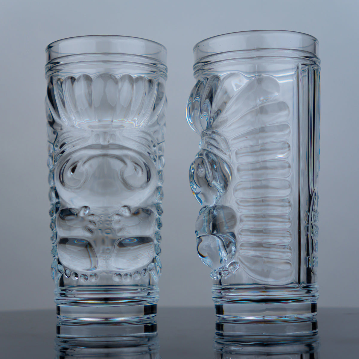 Two clear glass tumblers with intricate designs on a gray background