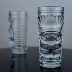 Tiki glasses pair, embossed face, dark surface