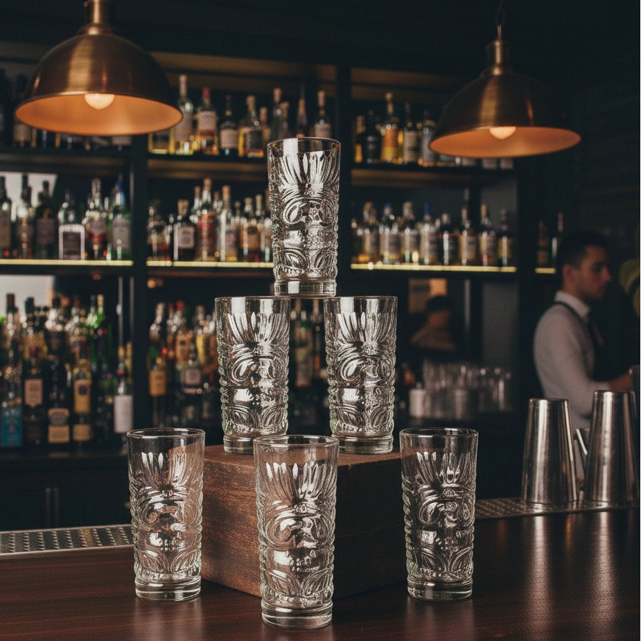 Decorative glass tumblers on a bar counter with a well-stocked bar in the background.