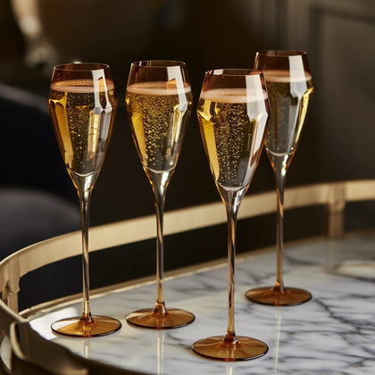 Four champagne flutes filled with sparkling wine on a marble surface.