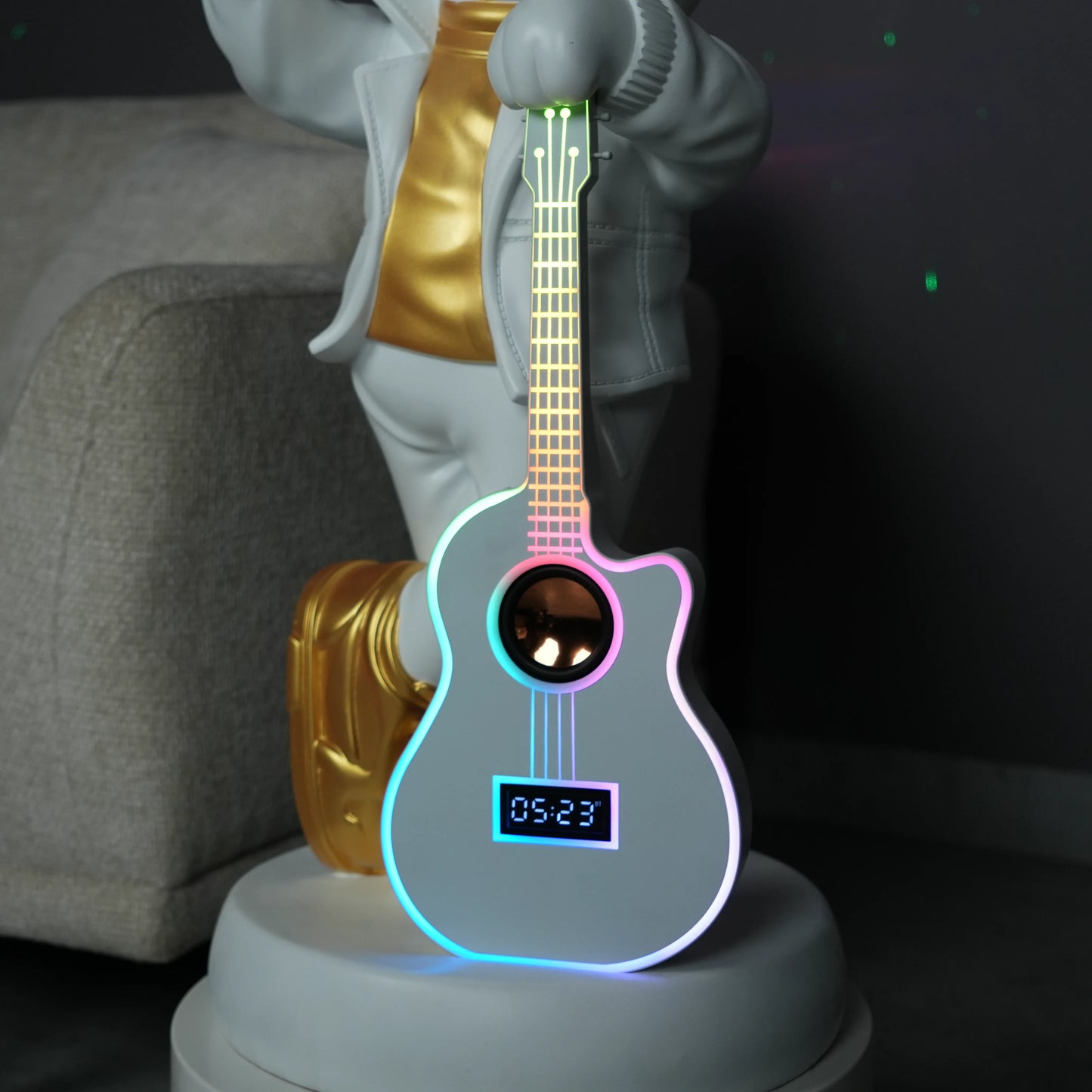 White-and-gold astronaut statue holding a moon projector balloon with a guitar-shaped Bluetooth speaker, standing on a pedestal with galaxy projection in the background.