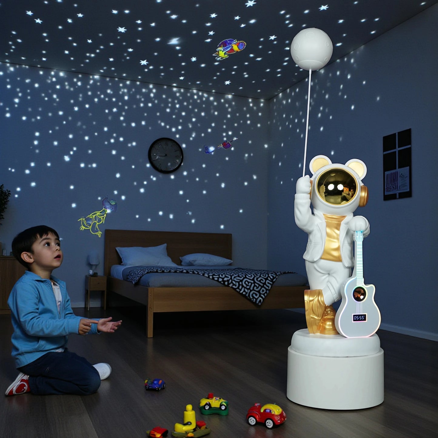 White-and-gold astronaut statue holding a moon projector balloon with a guitar-shaped Bluetooth speaker, standing on a pedestal with galaxy projection in the background.