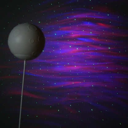 Beige and white astronaut statue with a chrome silver visor holding a moon-shaped projector balloon and a silver-tone guitar Bluetooth speaker, standing on a pedestal.