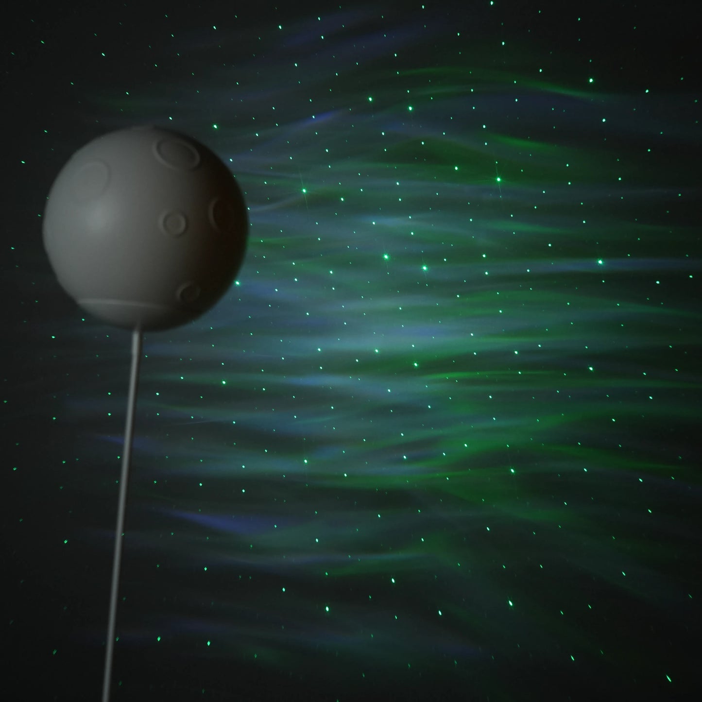 Beige and white astronaut statue with a chrome silver visor holding a moon-shaped projector balloon and a silver-tone guitar Bluetooth speaker, standing on a pedestal.