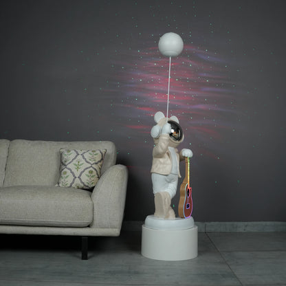Beige and white astronaut statue with a chrome silver visor holding a moon-shaped projector balloon and a silver-tone guitar Bluetooth speaker, standing on a pedestal.