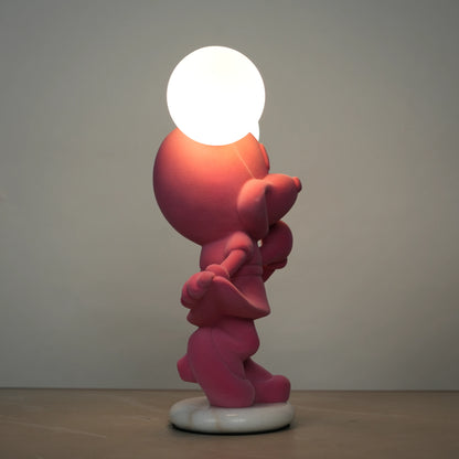 Standing pink flocked character lamp with two glowing ear-shaped bulbs on a white base.