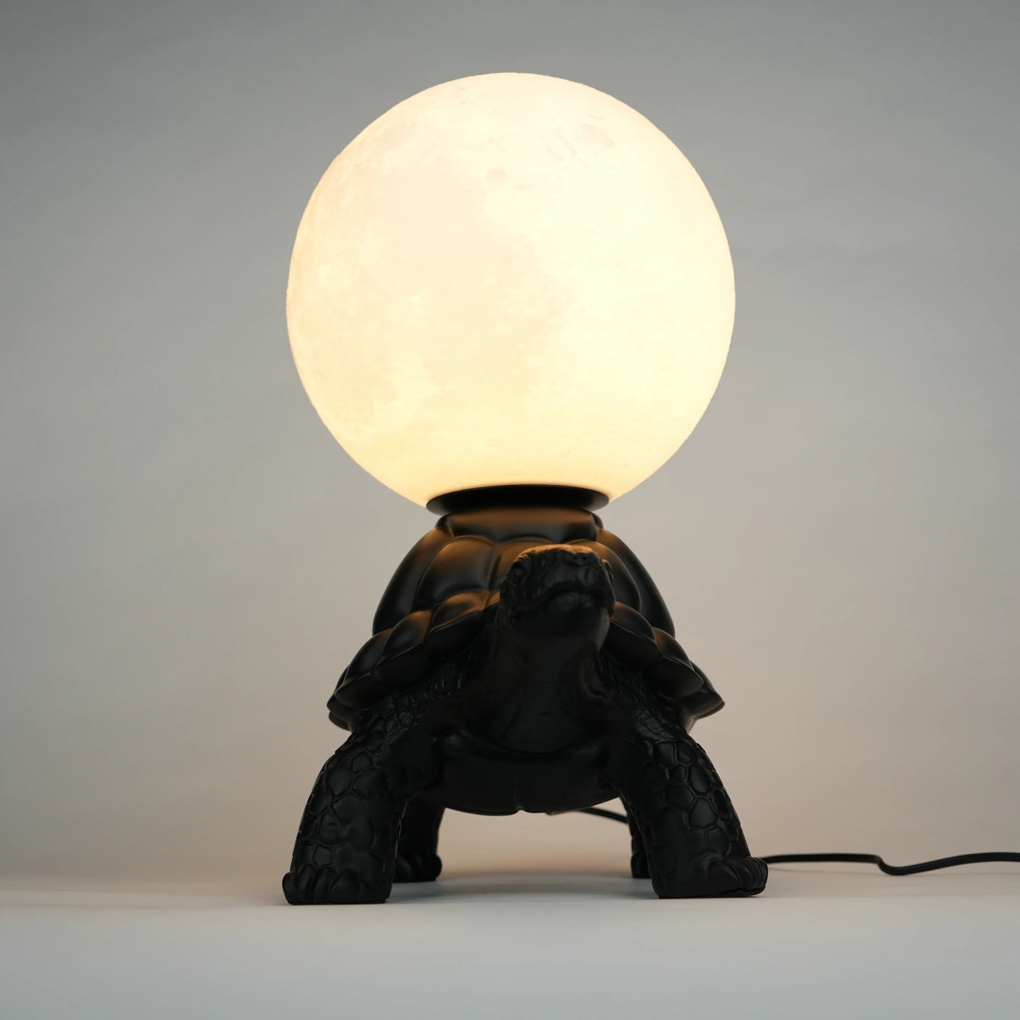 Black tortoise sculpture lamp with a glowing moon orb on its shell.