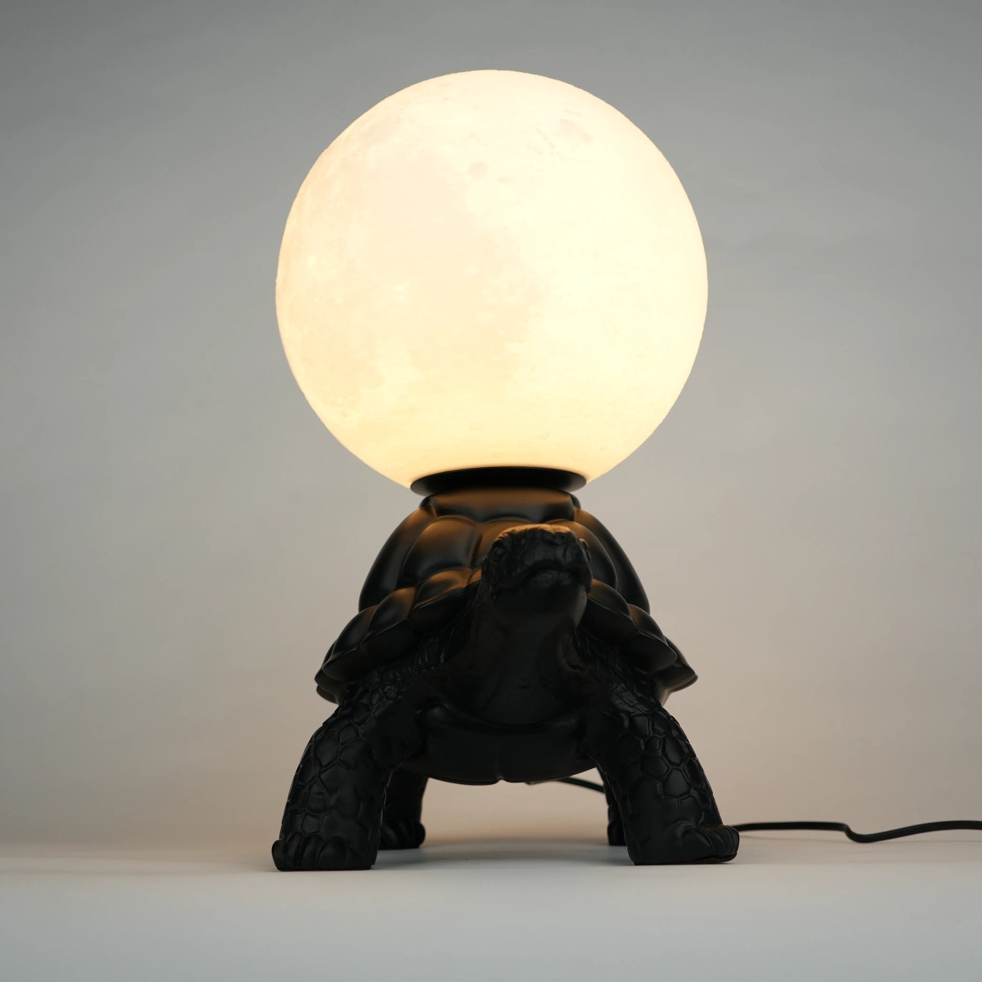 Black tortoise sculpture lamp with a glowing moon orb on its shell.