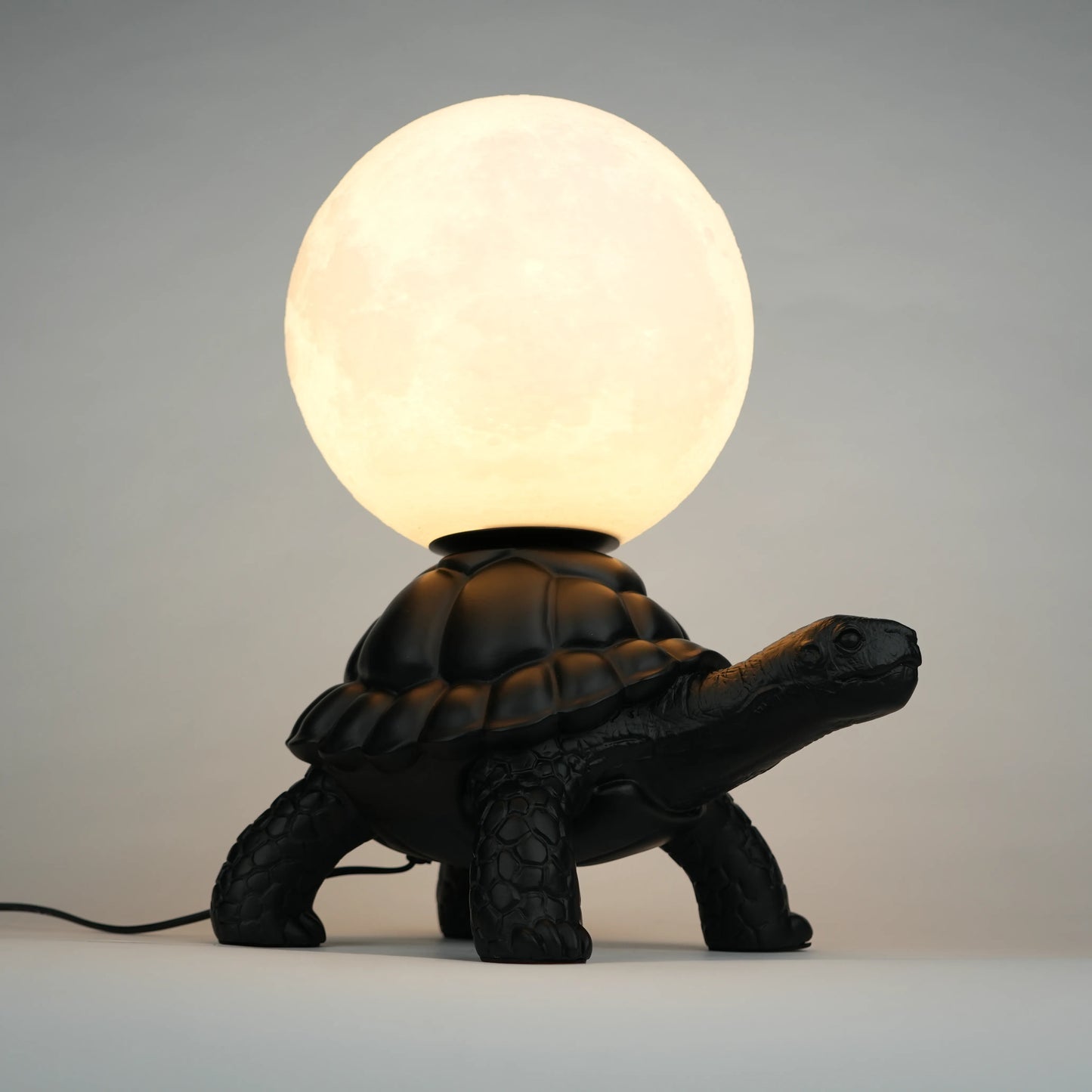 Black tortoise sculpture lamp with a glowing moon orb on its shell.