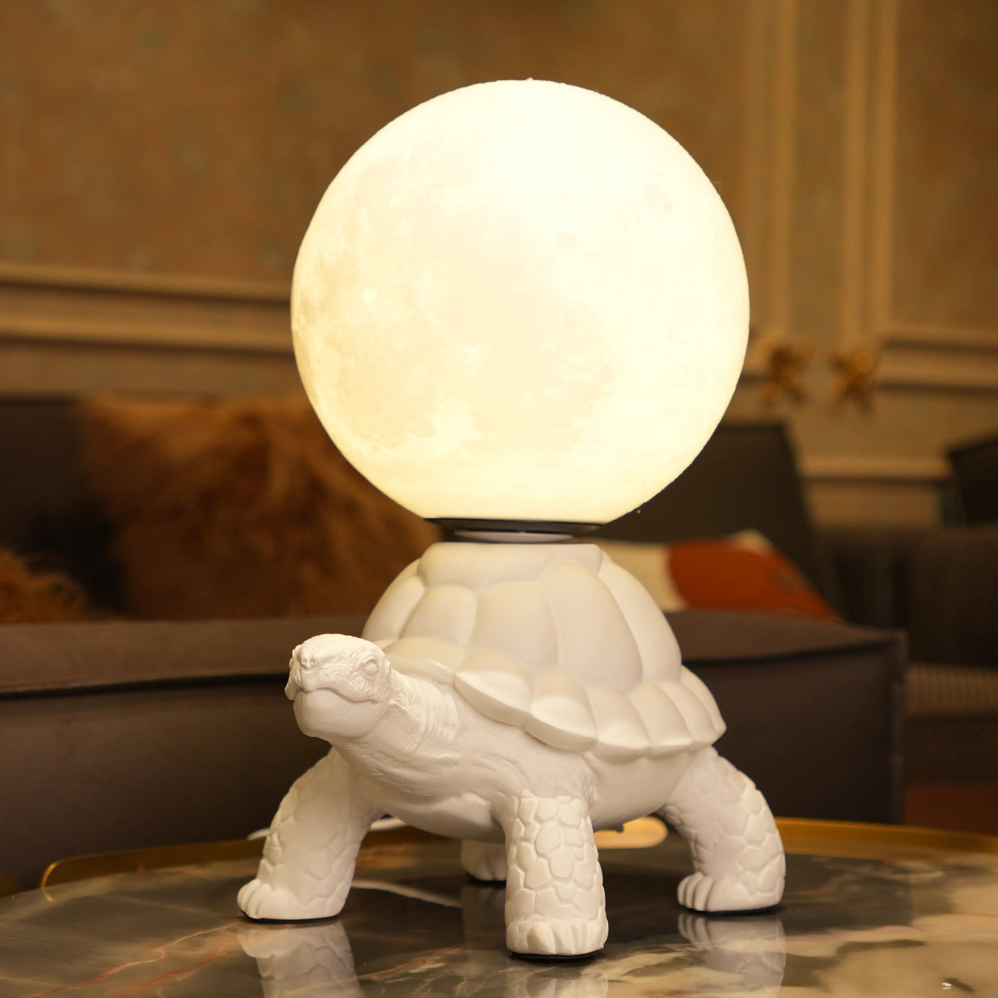White tortoise sculpture lamp with a glowing moon orb placed on its shell.