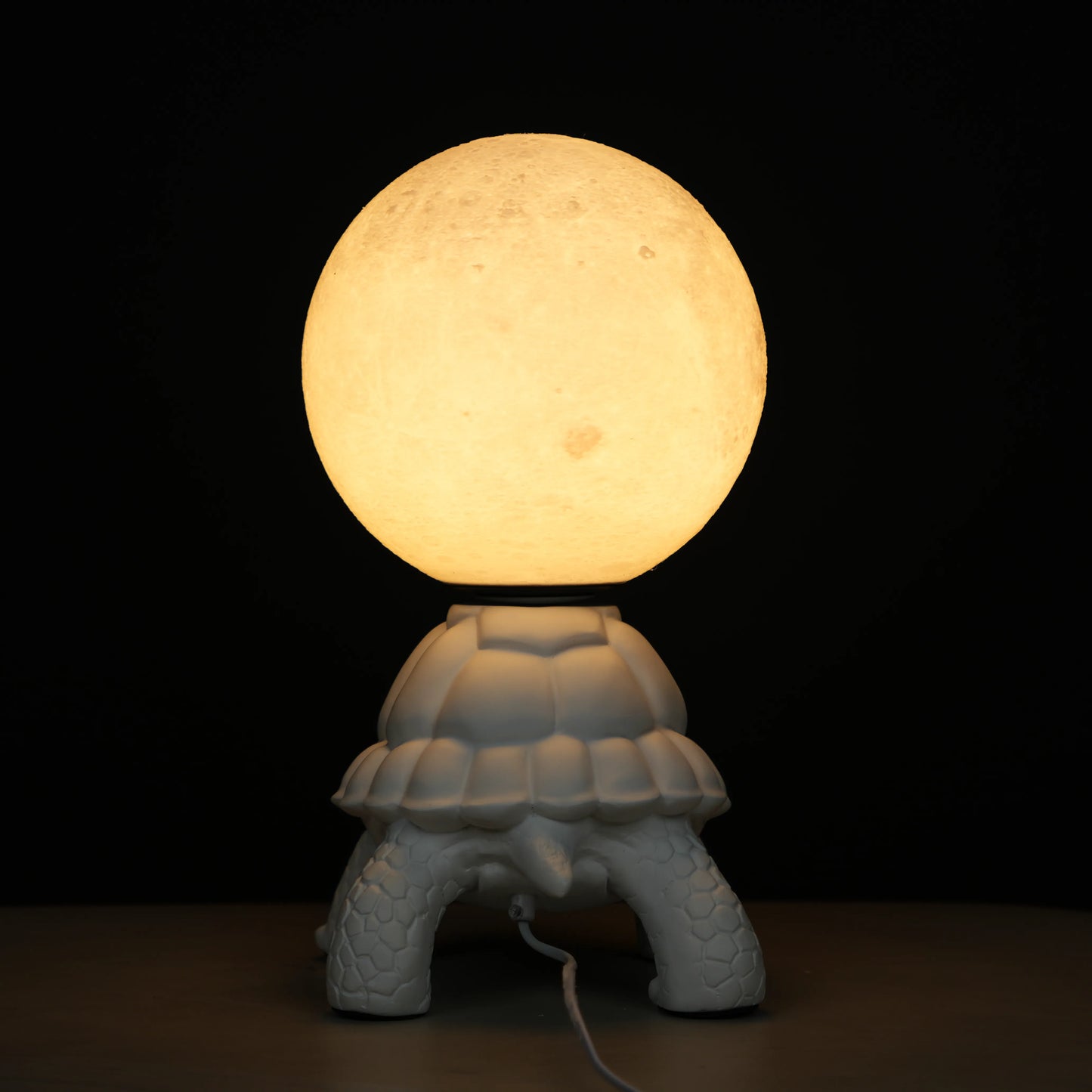 White tortoise sculpture lamp with a glowing moon orb placed on its shell.