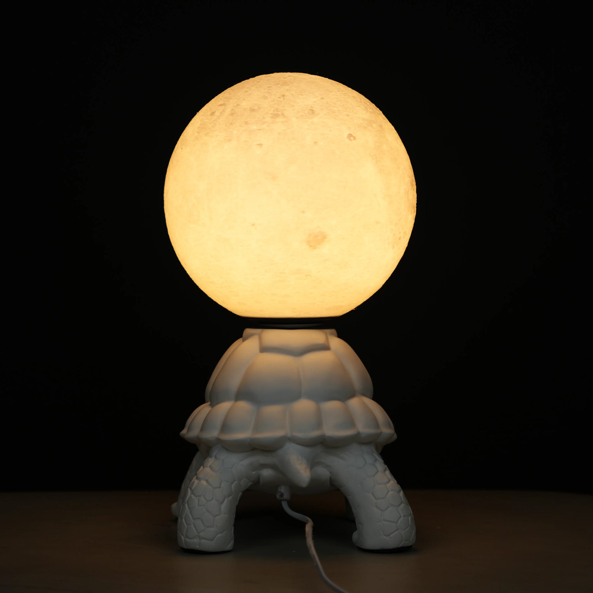 White tortoise sculpture lamp with a glowing moon orb placed on its shell.