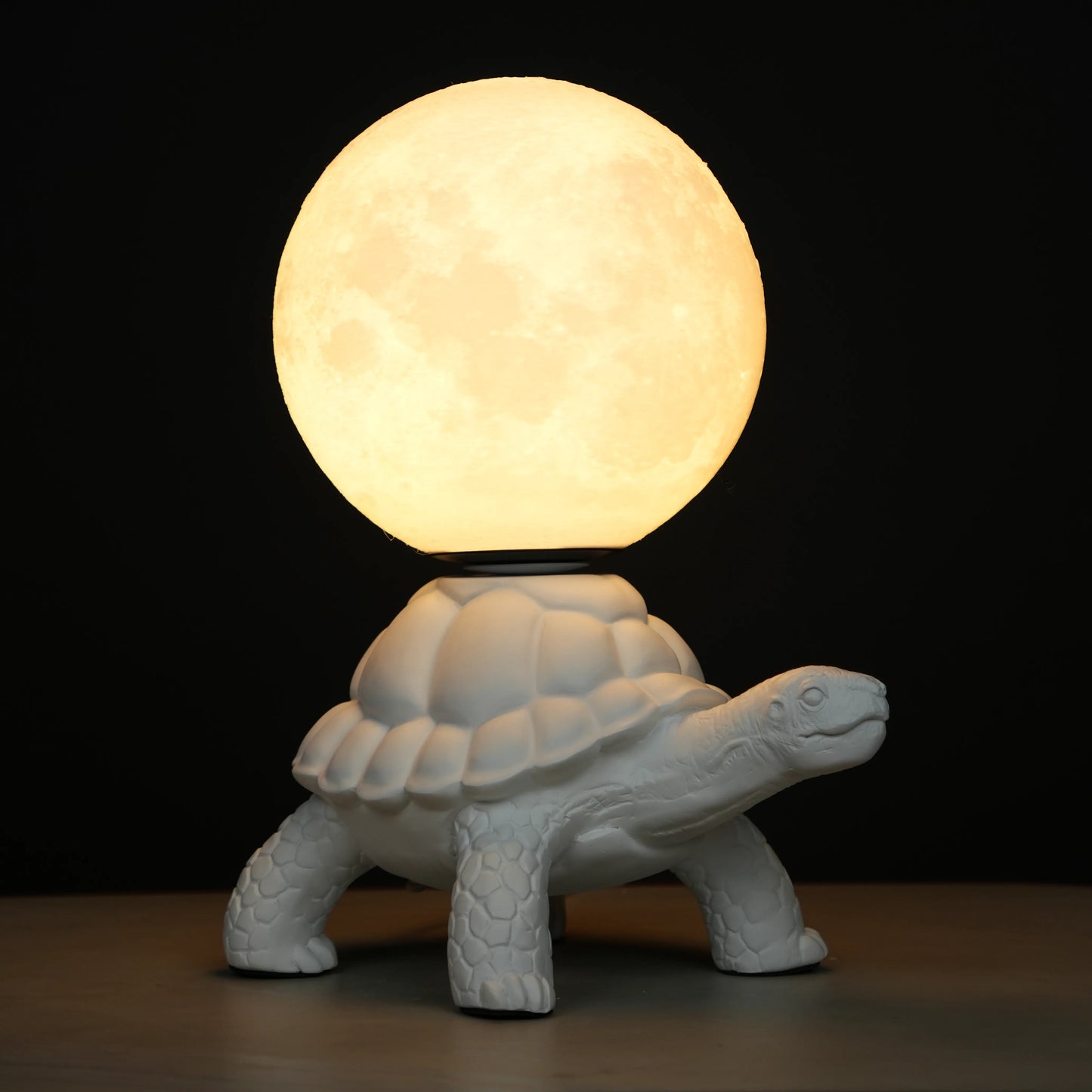 White tortoise sculpture lamp with a glowing moon orb placed on its shell.