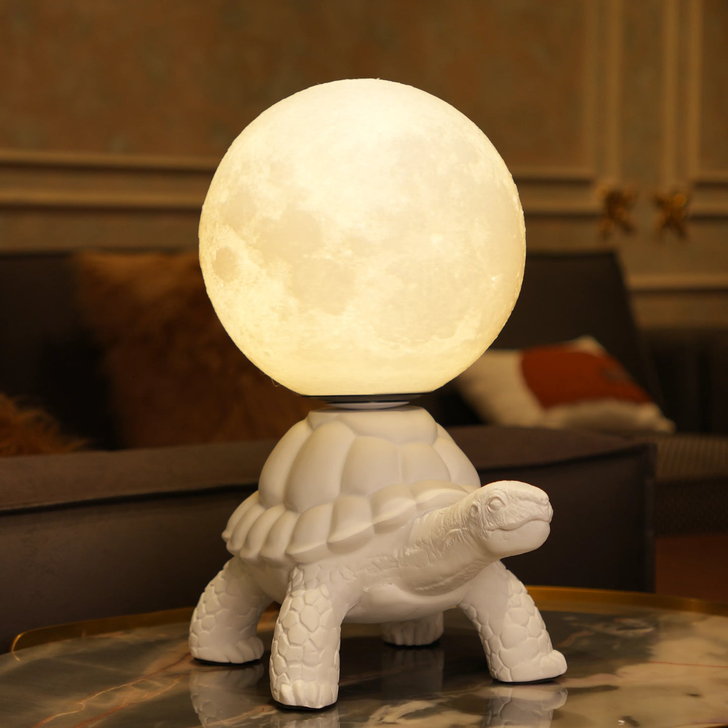 White tortoise sculpture lamp with a glowing moon orb placed on its shell.