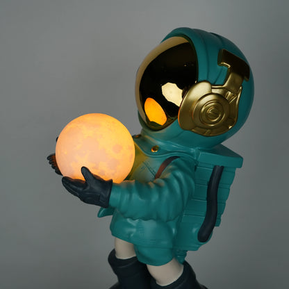 Teal astronaut figurine with gold visor holding a glowing orb while standing on a large crater-textured moon base.