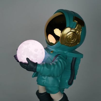 Teal astronaut figurine with gold visor holding a glowing orb while standing on a large crater-textured moon base.
