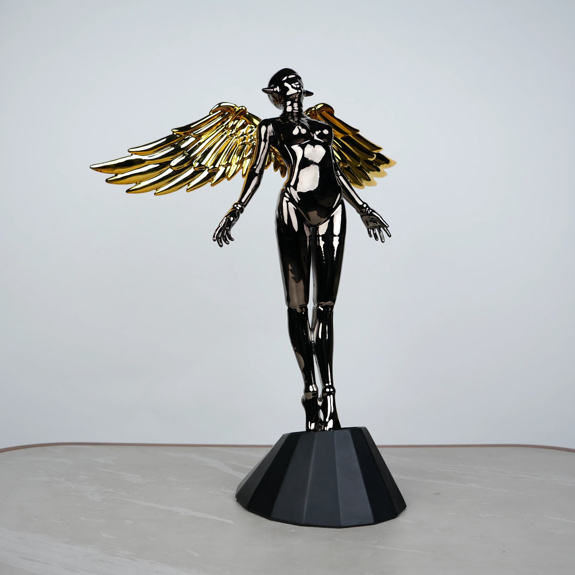 Celestial Chrome Angel Sculpture with reflective chrome body and gold wings on pedestal