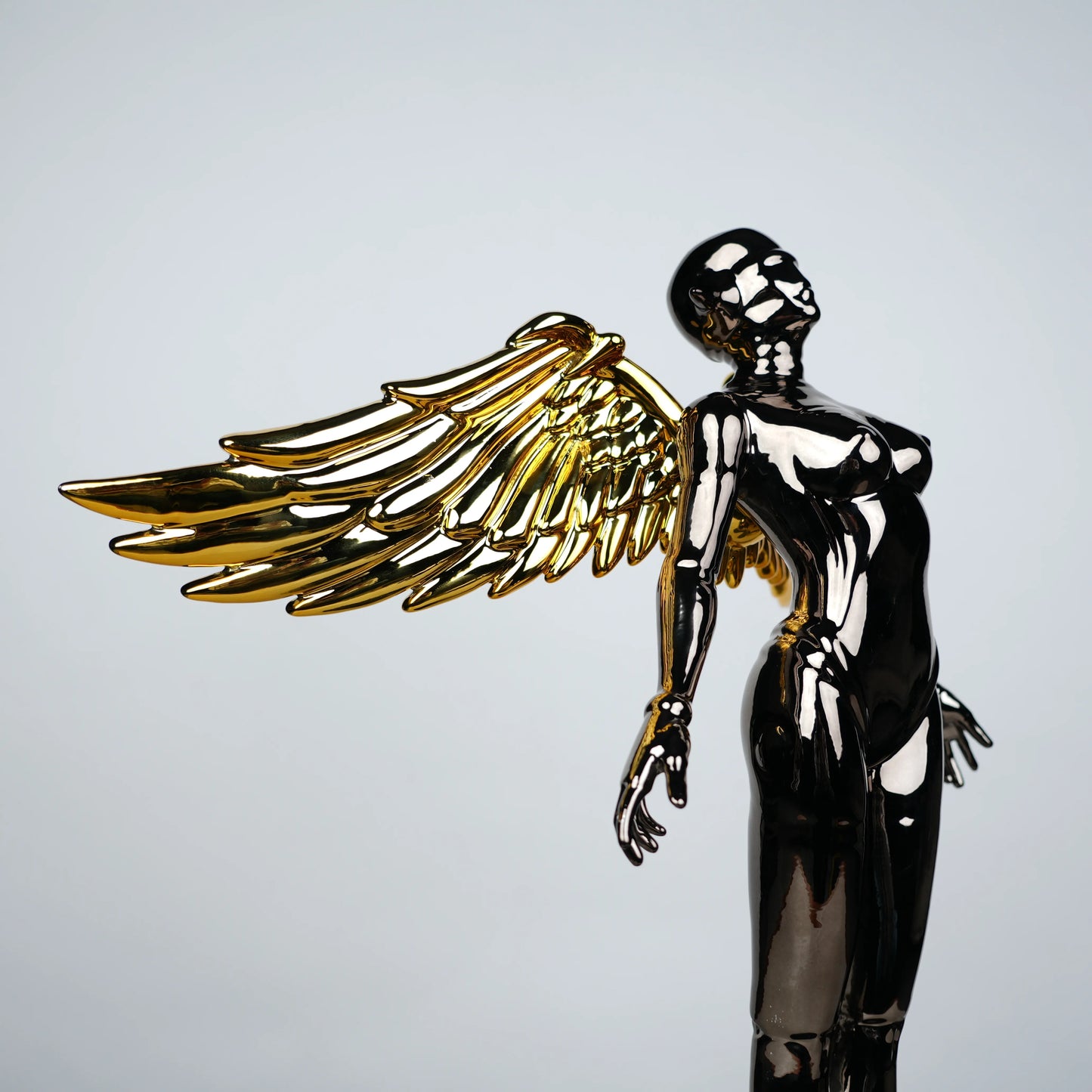 Celestial Chrome Angel Sculpture with reflective chrome body and gold wings on pedestal