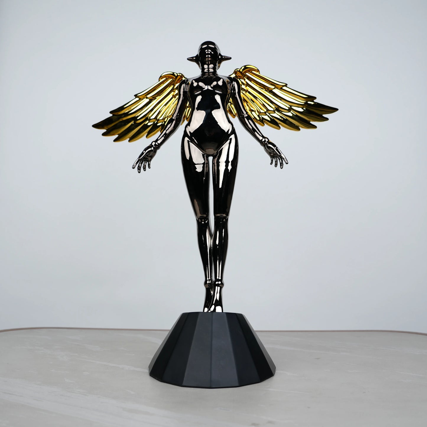 Celestial Chrome Angel Sculpture with reflective chrome body and gold wings on pedestal