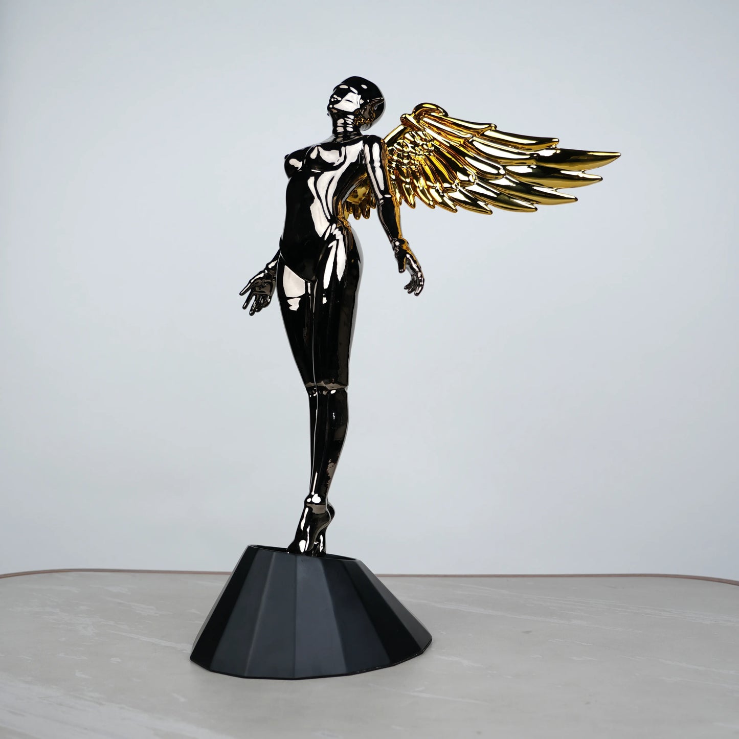 Celestial Chrome Angel Sculpture with reflective chrome body and gold wings on pedestal