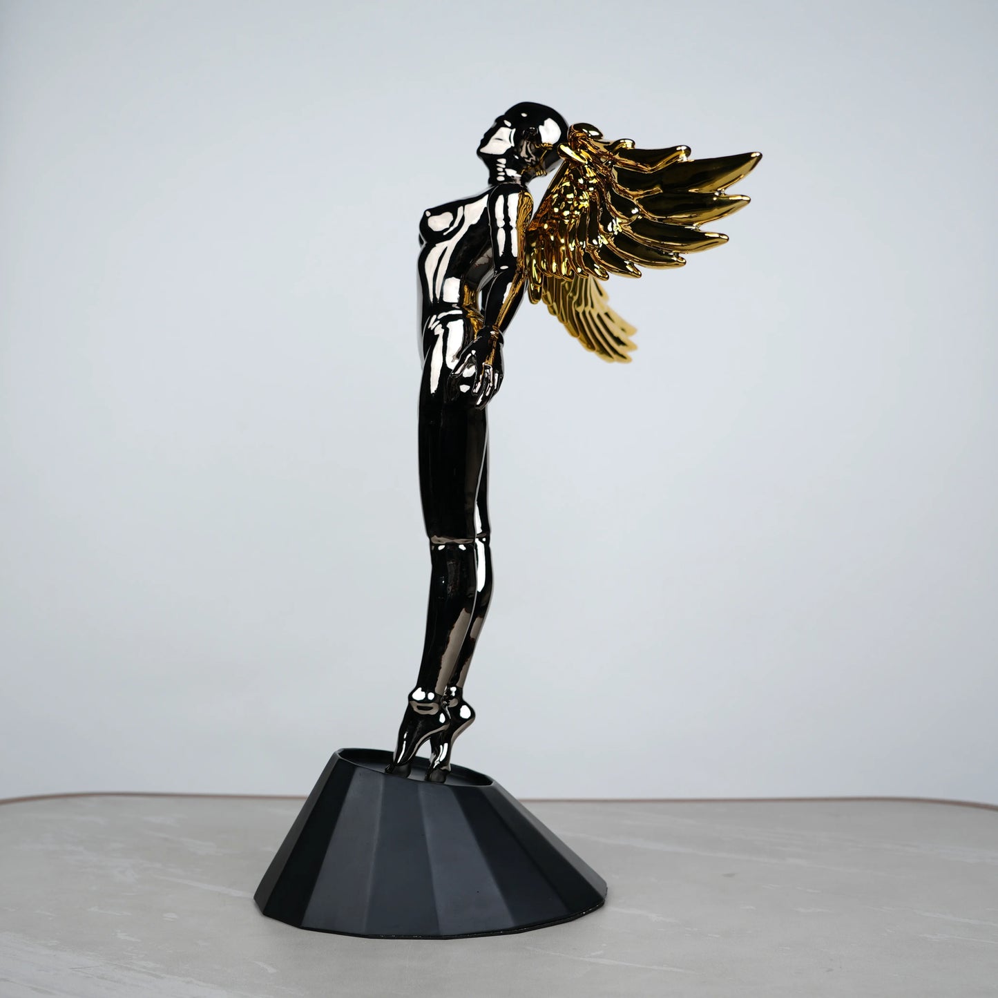 Celestial Chrome Angel Sculpture with reflective chrome body and gold wings on pedestal