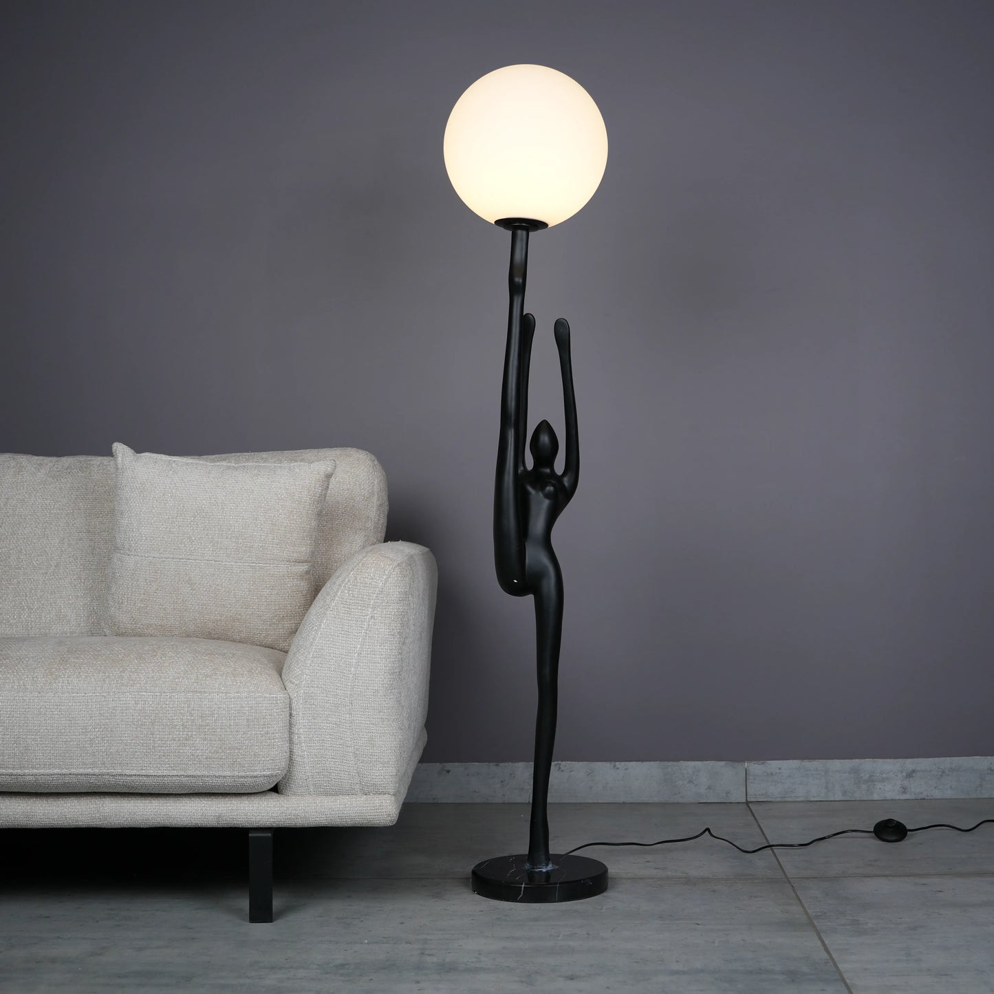Elegant Human Stretch Lamp – tall matte black human-form sculpture holding a glowing orb floor lamp.