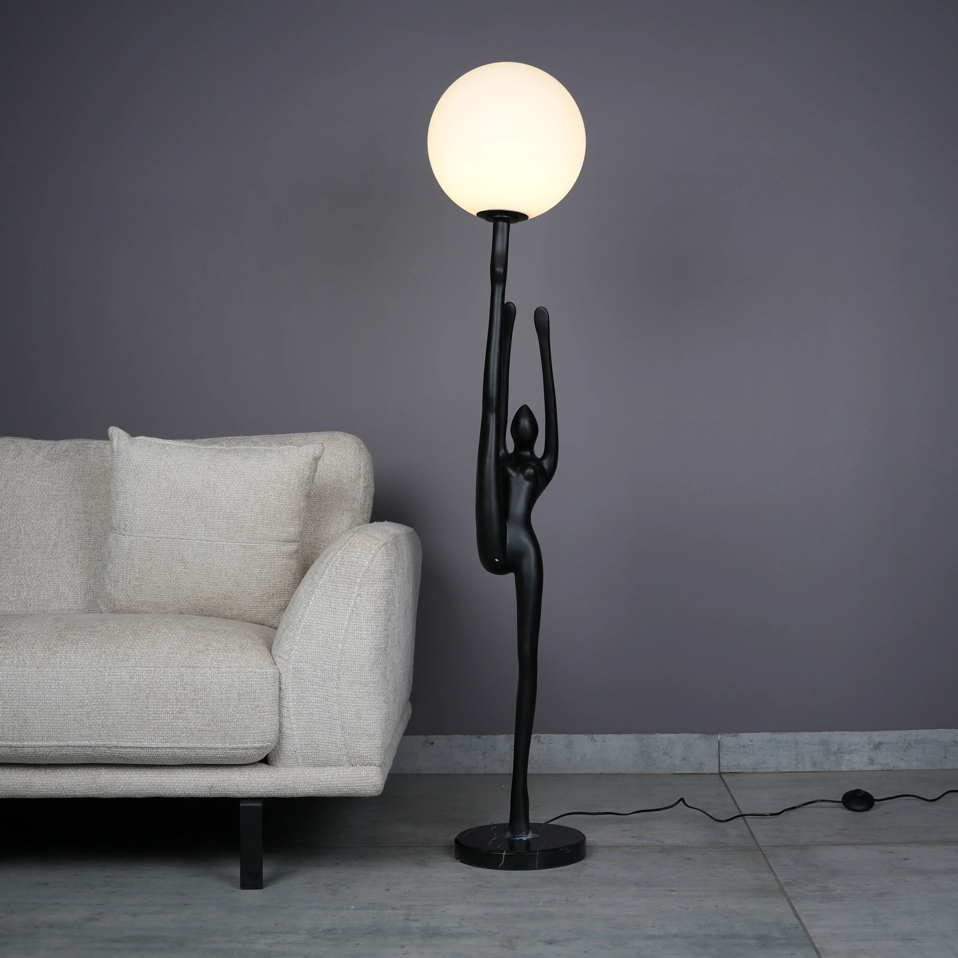 Elegant Human Stretch Lamp – tall matte black human-form sculpture holding a glowing orb floor lamp.