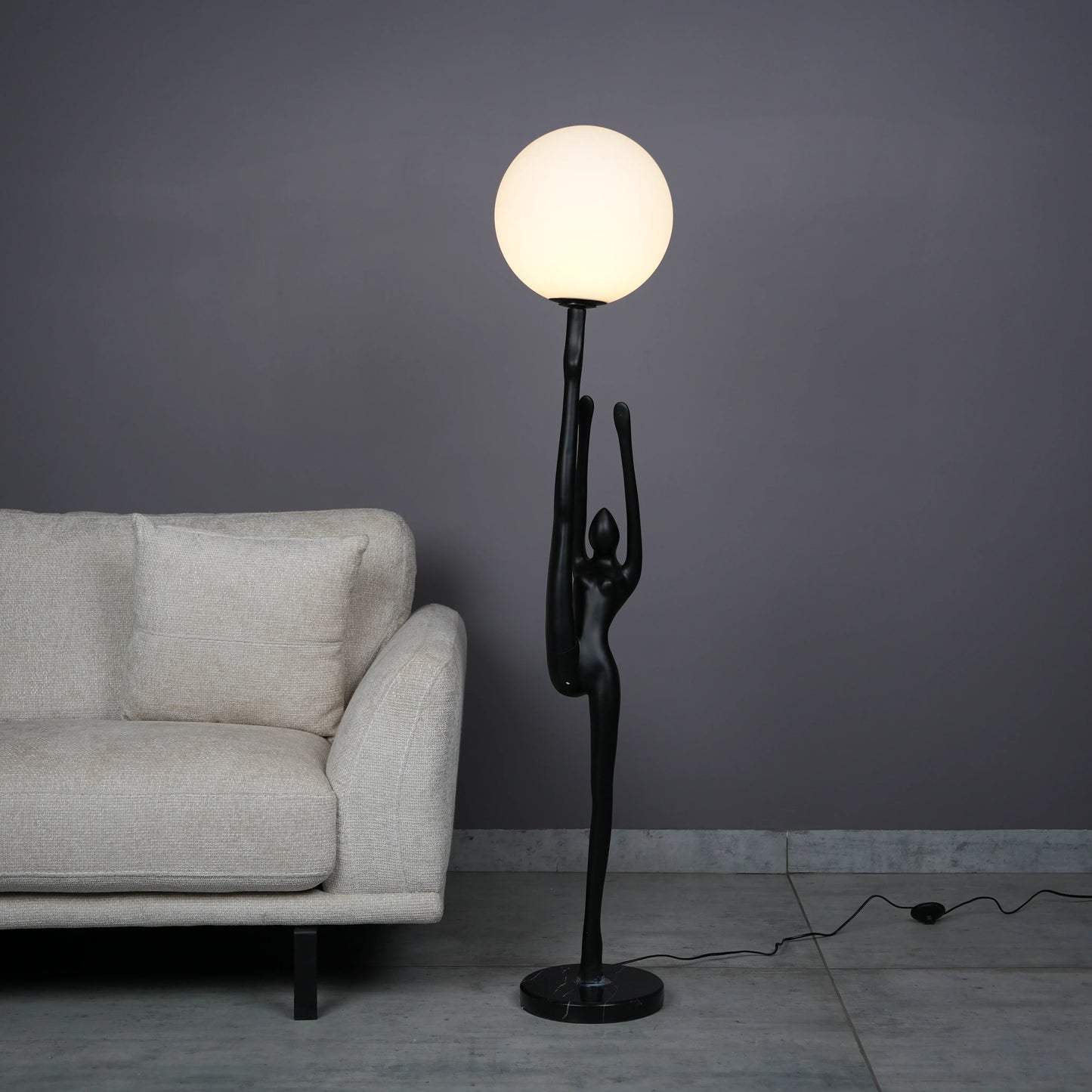 Elegant Human Stretch Lamp – tall matte black human-form sculpture holding a glowing orb floor lamp.