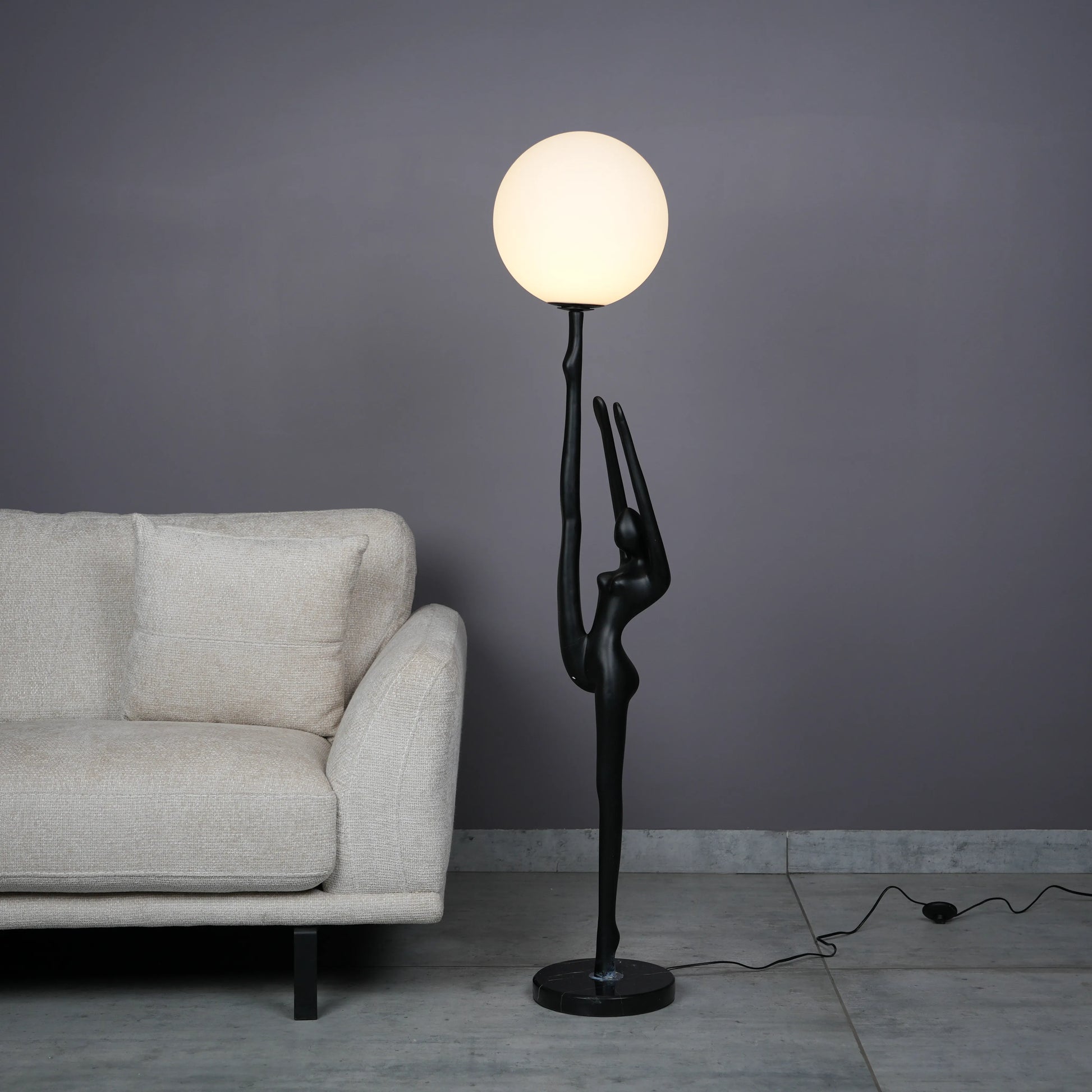 Elegant Human Stretch Lamp – tall matte black human-form sculpture holding a glowing orb floor lamp.