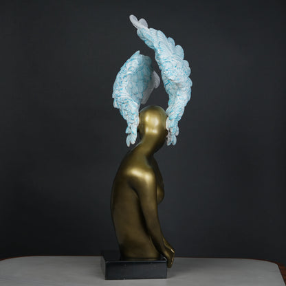 Gold-bodied woman sculpture with large white and blue feathered wings on a black base — luxury artistic décor piece.