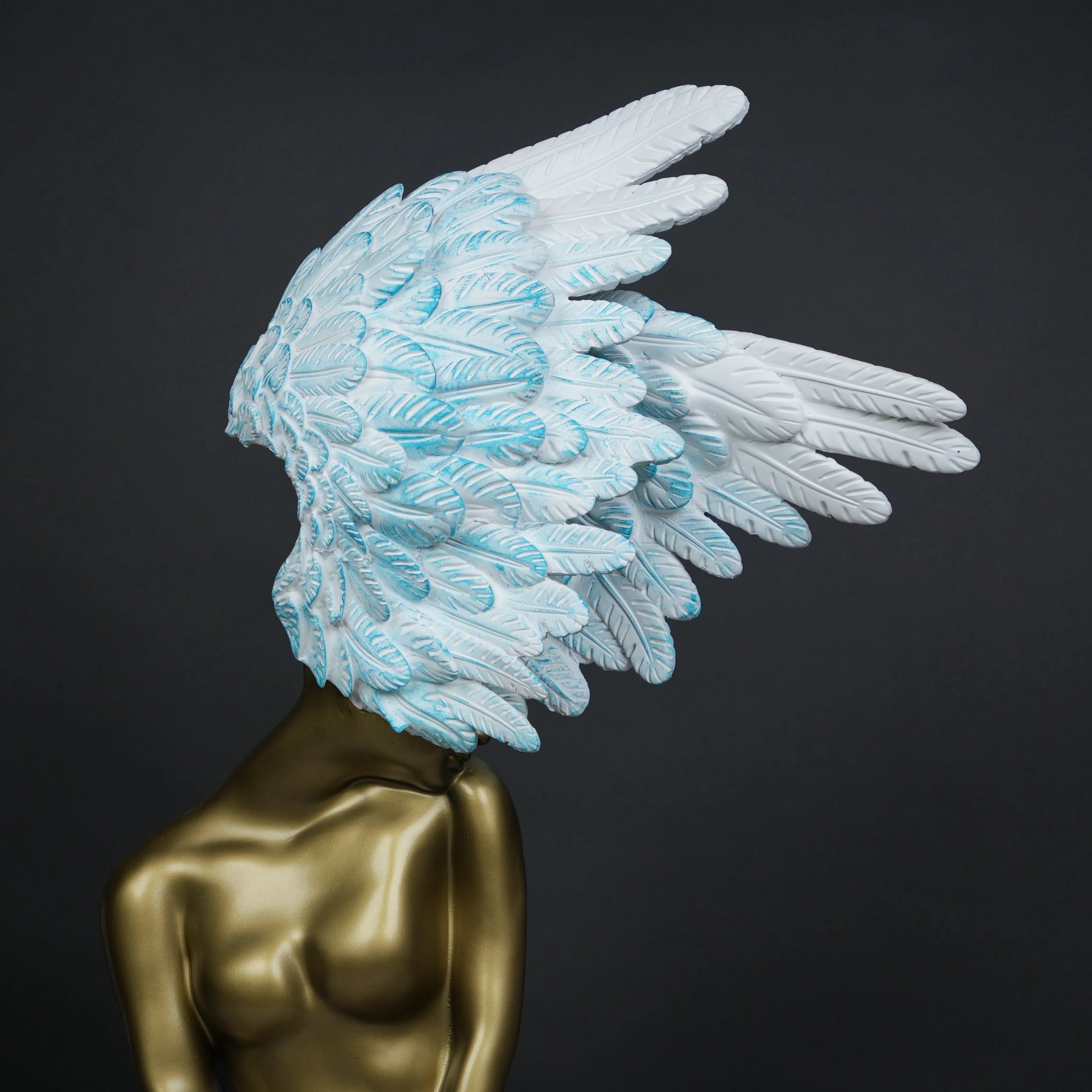 Gold-bodied woman sculpture with large white and blue feathered wings on a black base — luxury artistic décor piece.