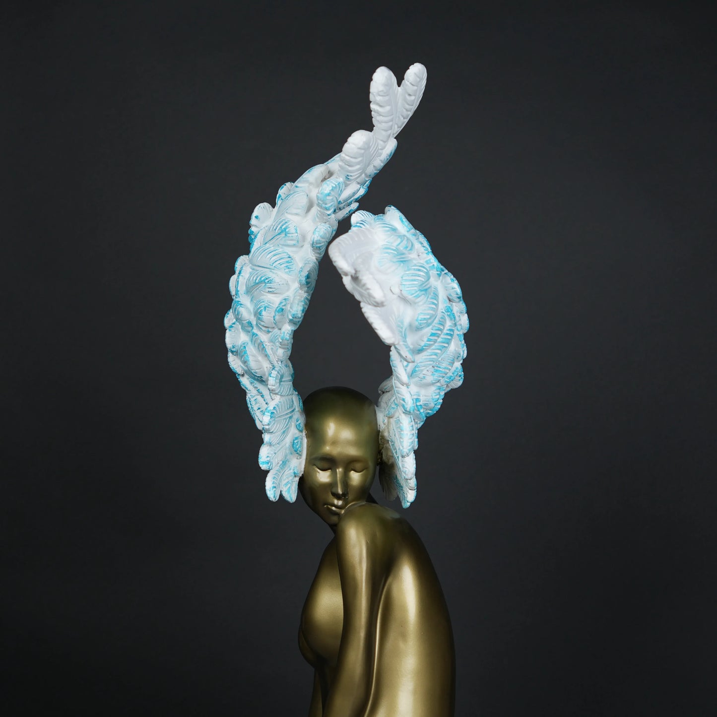 Gold-bodied woman sculpture with large white and blue feathered wings on a black base — luxury artistic décor piece.